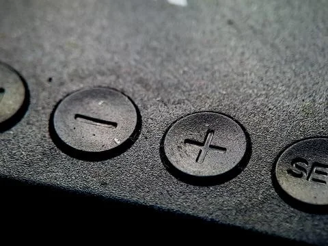 A dark, textured surface featuring raised circular controls with symbols an.. Stock Photos