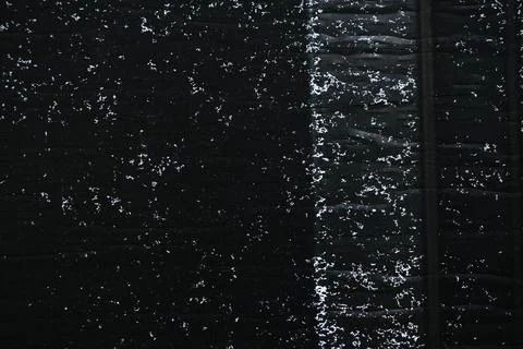 Dark textured surface with scattered white specks and a prominent vertical Foto stock