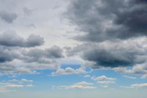 Dark thunderclouds are approaching the blue sunny sky. Change of weather. Stock Photos