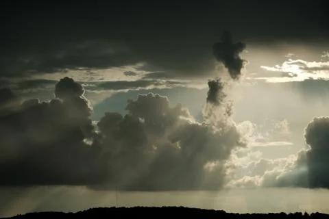 Dark thunderclouds pierced by the rays of the sun. Stock Photos