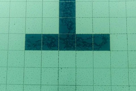 Dark tiles of a pool in the shape of a T Foto stock