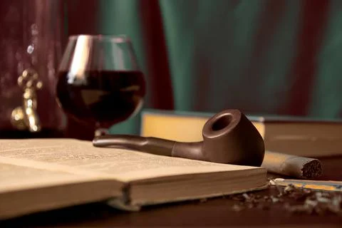Dark toned image with smoking pipe, tobacco, book and brandy in the parlor Fotos de archivo