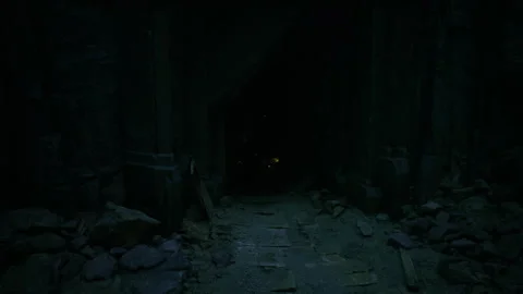 Dark trail with flickering light. Uneven rocky path towards faint glow 스톡 동영상 335596384
