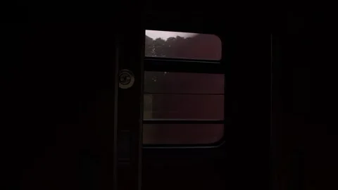 Dark train compartment as another locomotive speeds past at night. Red streaks Stock Footage 320605902
