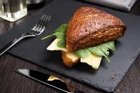 Dark triangular sandwich with cheese and greens on a black board. Stock Photos