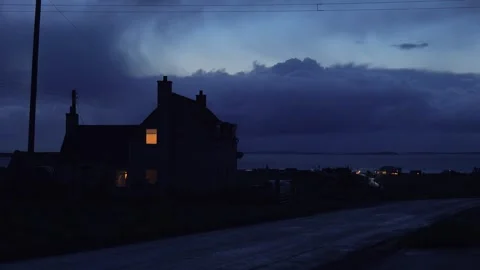 Dark twilight scene of a remote house by the water with dramatic clouds and.. Stock Footage 337803554