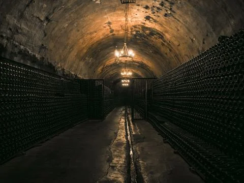 Dark underground wine cellar featuring endless rows of bottles illuminated by 스톡 사진