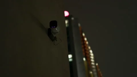 DARK view over a CCTV camera against a modern building at night Stock Footage 224175388