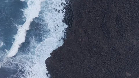 Dark volcanic rocks colliding with powerful Atlantic waves, displaying stark Stock Footage 308402832