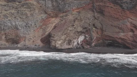 Dark volcanic shoreline hugging rugged cliffs in Playa Bujaren, powerful waves Stock Footage 308394530