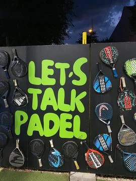 Dark wall decorated with padel rackets features the text 'LET'S TALK PADEL' Stock Photos