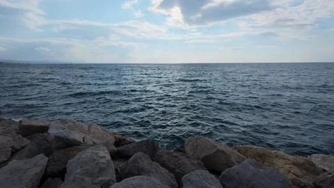 Dark wavy sea under heavy sky with stone breakwater and wide horizon Stock Footage 337460206