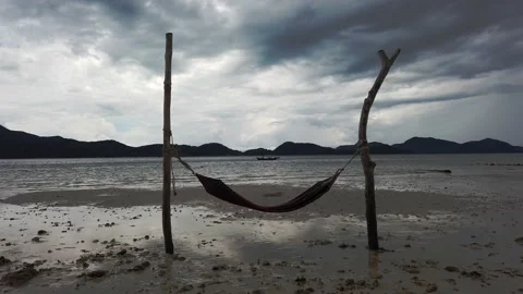 Dark Windy Empty Beach with Single boat Between a Makeshift Hammock Stock Footage 148375798