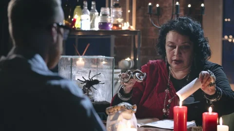 Dark witch performing spell for client in her office Stock Footage 136889342