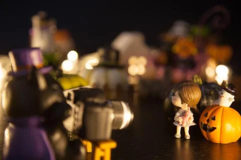 Dark wizard cat using camera to take girl photo with pumpkins and ghost in fr Stock Photos