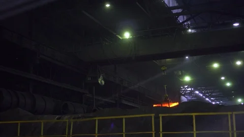 In a dark workshop, claws lift a red-hot metal rod and transport it Stock Footage 115928434