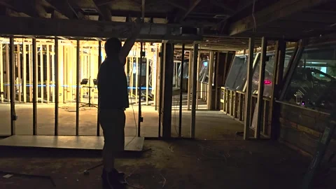 Darkly lit scene pulling network cable through rafters during a building Stock Footage 266138122