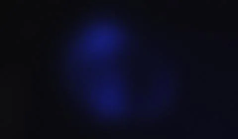 Darkness holds a single glowing blue shape. Soft light pulses subtly within.. Stock Illustration