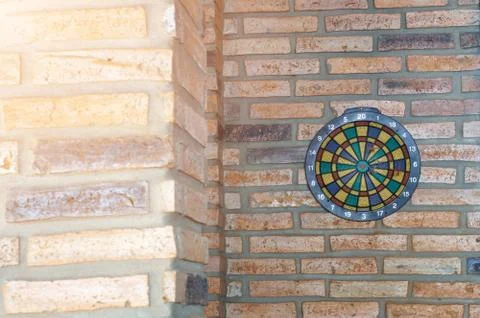Dart arrow missing the center of target. dartboard on brick wall with sunrise Stock Photos