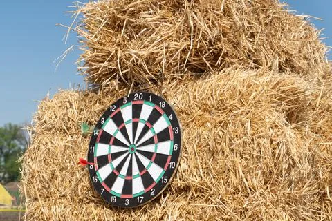 A dartboard on a haystack with a red dart missing the board Stock Photos