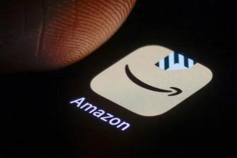 Das Logo der Amazon App ist neben einem Finger auf einem Smartphone zu seh... Stock Photos