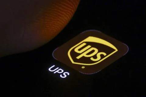 Das Logo der UPS App (United Parcel Service) ist neben einem Finger auf ei... 库存照片