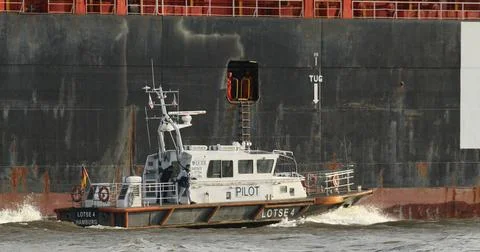 Das Lotsenboot Lotse 4 fährt neben einem Containerschiff entlang. Altona H.. Stock Photos