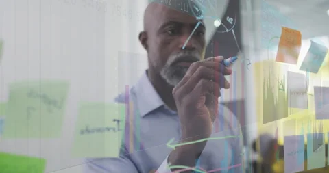 Data analyst approaching glass partition annotating charts for highlighting Stock Footage 316089604