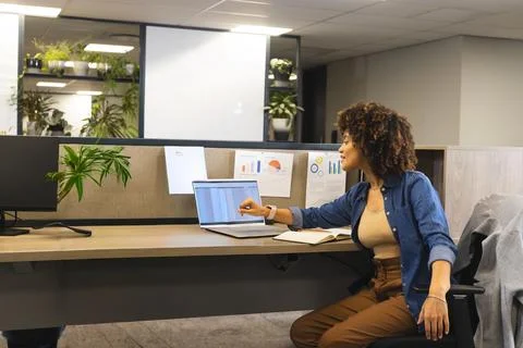 Data analyst leaning forward pointing at laptop after spotting chart generating 스톡 사진
