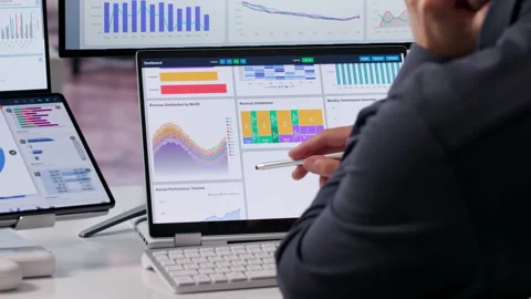 Data Analyst Reviewing Financial KPIs On Dual Screens Stock Footage 339889571