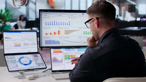 Data Analyst Reviewing Financial KPIs On Dual Screens Stock Footage 340995309