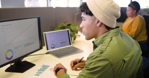 Data analyst spotting growth charts and studying bar chart at desk while Stock Footage 339320576