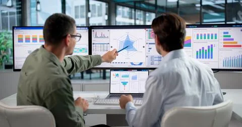 Data Analysts Collaborate Closely, Reviewing Financial Dashboards On Laptops. Foto stock