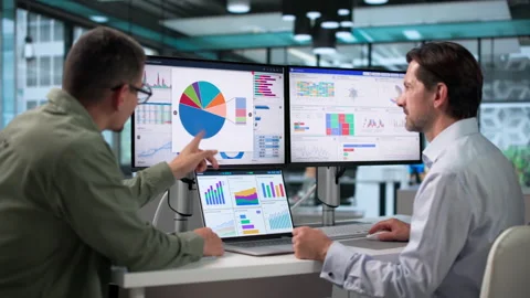 Data Analysts Discussing Financial Dashboard Insights During A Busy Office Stock Footage 346327772