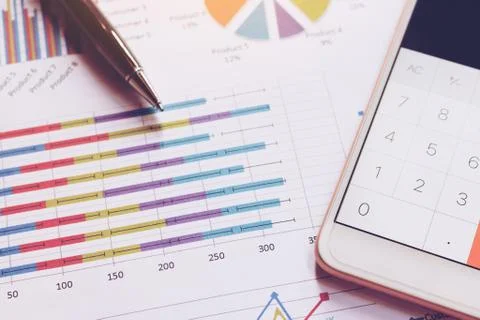 Data analyzing with calculator in smart phone and pen on charts and graph. Stock Photos