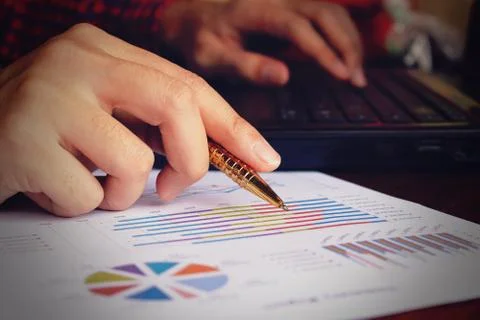Data analyzing with laptop and pointing pen at charts and graph to find out.. Stock Photos