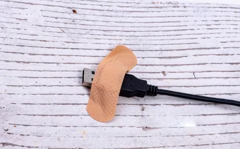 Data cable with a plaster glued to the white wood Stock Photos