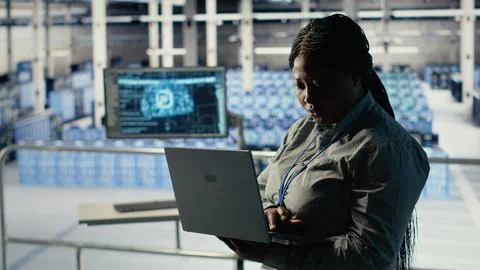 Data center admin checks AI dashboard using laptop during rigs systems review. Stock Photos