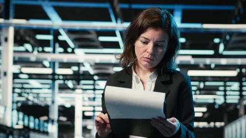 Data center admin reading paperwork, inspecting blue wireframe mesh hardware Stock Footage 329325079