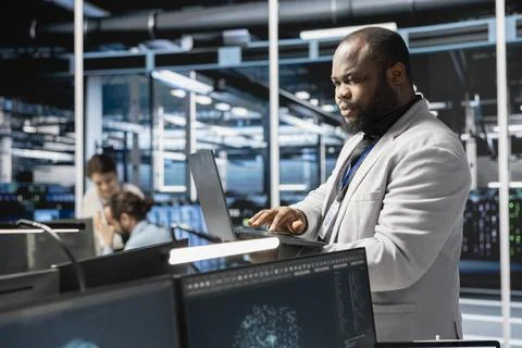 Data center admin using laptop to update servers tech, configuring gear Foto stock