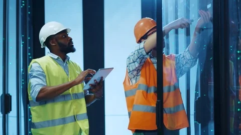 Data center blackout. Two diverse electrical technicians fixing power error Stock Footage 120746834