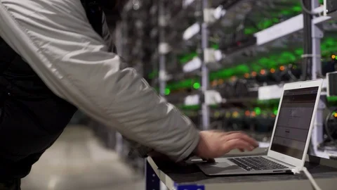 Data center diagnostics technician works and types on laptop. Mining equipment Stock Footage 126691076