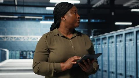 Data center employee uses tablet to manage software updates for system stability Stock Photos