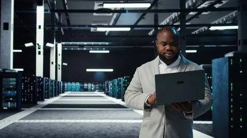 Data center engineer coding on laptop, doing software updates for mainframes Stock Photos