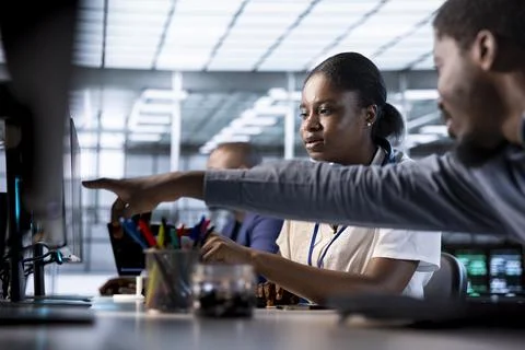 Data center engineer helping colleague, pointing finger to screen, Foto stock