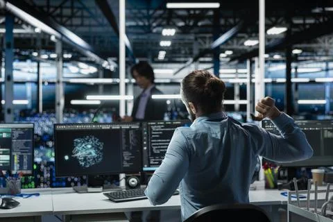 Data center engineer stretching at workstation to relieve back fatigue Stock Photos