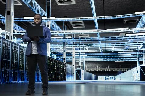 Data center engineer uses laptop to manage IT infrastructure rigs Stock Photos
