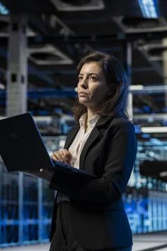 Data center female engineer using laptop, managing server virtualization Stock Photos