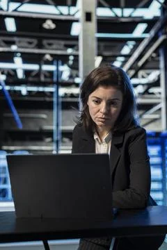 Data center female engineer using laptop to review equipment diagnostics Stock Photos