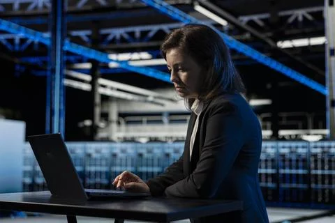 Data center female programmer using laptop to inspect infrastructure Stockfoto's